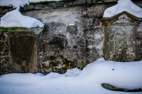 Zvláštní kamenná lebka na hřbitovní zdi.